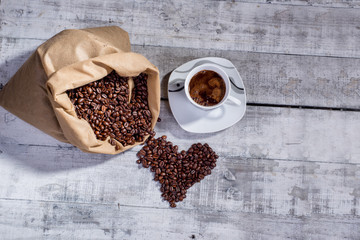 Heart of coffee beans and cup of fresh coffee