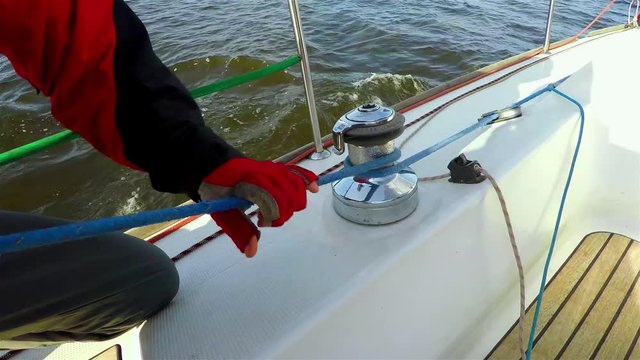 Yachtsman in red gloves sheets with windlass. 4K