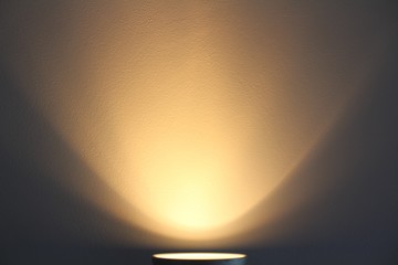 The lamp shines with warm light on the wall