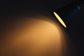 The lamp shines with warm light on the wall