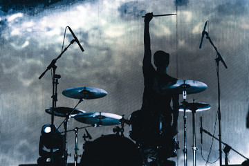 Rock band performs on stage. Musician drummer silhouette in the concert. silhouette of drum player...