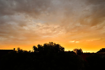 Fototapeta na wymiar Chmury na niebie nad budynkami mieszkalnymi podczas zachodu słońca.