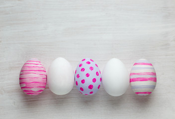 Easter eggs painted in pastel colors on white wooden background