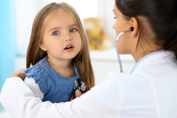 Fototapeta premium Doctor examining a little girl by stethoscope