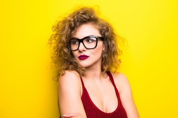 Beauty portrait of young american girl with curly hairstyle. Girl posing on yellow background, looking at camera, smiling. Studio shot.