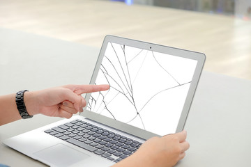 Left finger of woman, she pointing at the white screen laptop, the screen cracked and damaged.