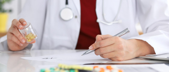 Close up of unknown female doctor typing on laptop computer while sitting  at the table. Medical staff, compulsory work concept