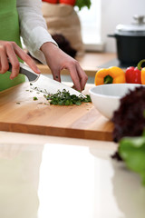 Close-up of human hands cooking vegetables salad in kitchen on the glass table with reflection. Healthy meal and vegetarian concept