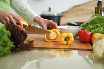 Close-up of human hands cooking vegetables salad in kitchen on the glass table with reflection. Healthy meal and vegetarian concept