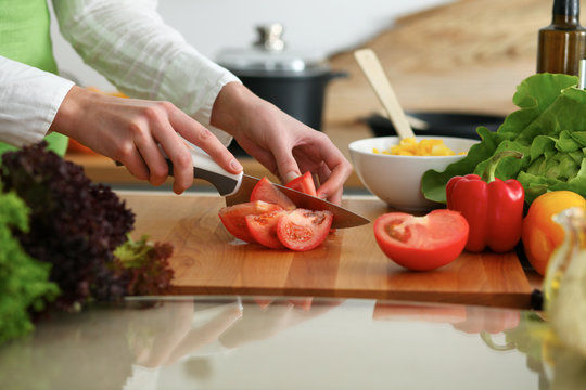 Close-up of human hands cooking vegetables salad in kitchen on the glass table with reflection. Healthy meal and vegetarian concept