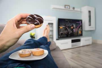 Person Eating Donut While Watching Television