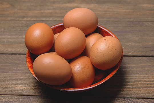 Brown wooden bowl with eggs.
