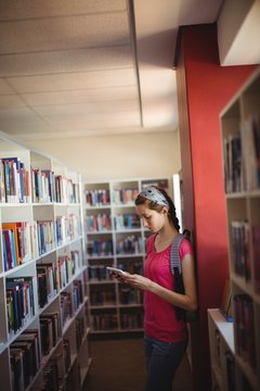 Attentive schoolgirl using digital tablet in library