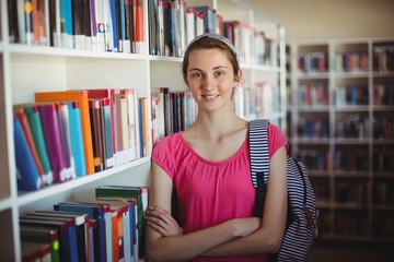 schoolgirl standing with arms crossed in library