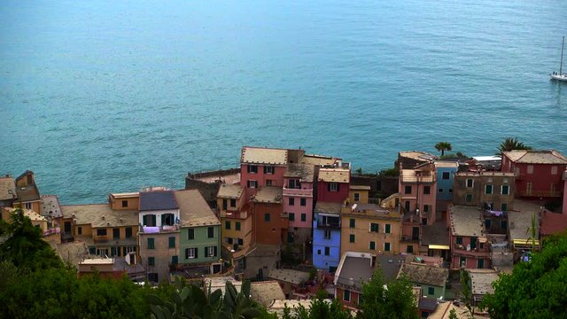 Beautiful scene of a sailboat gliding over the Mediterranean Sea behind a typical colorful italian village, in the Cinque Terre, Liguria, Italy