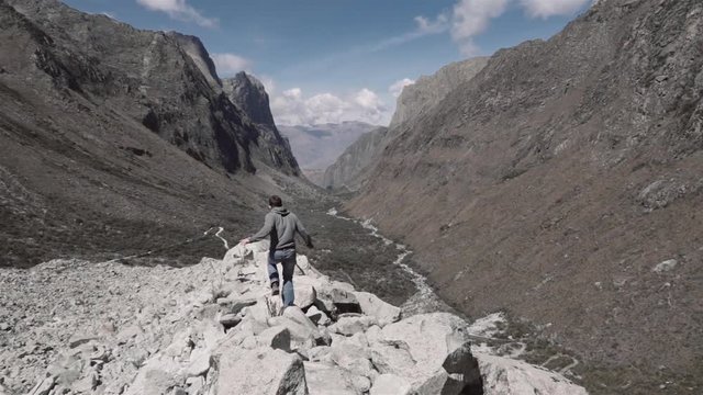 Man jumps on the rocks of a panoramic view on Huascaran Natural Park to escape of the storm. Slow motion