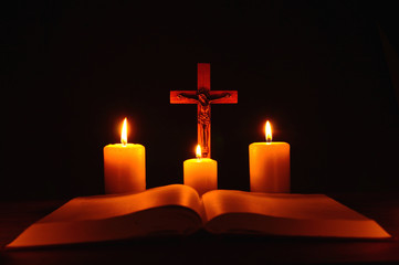 Crucifix and three burning candles with open bible on table in the darkness. Pray to Jesus Christ. Hope on good life. 4