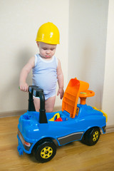 Fototapeta na wymiar Cute and serious Baby boy repairing a toy car indoors