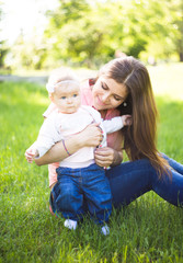 Happy young mother walking with her cute baby at summer sunny day