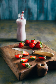 Cutting strawberries on wooden cutting board and strawberries milkshake