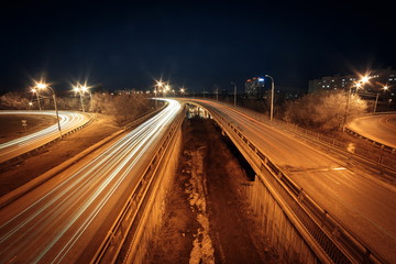 Fototapeta na wymiar Light trails at night on the road with overpass