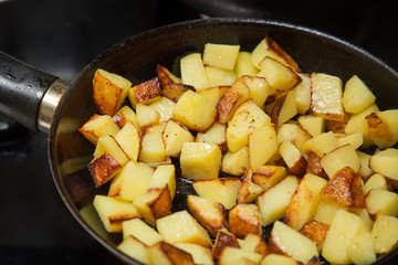 Fresh potatoes fried in a pan with butter close up