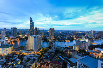 Fototapeta na wymiar Night light of Bangkok. view light blue background of glass high rise building skyscraper commercial of future. Business concept of success industry tech architecture
