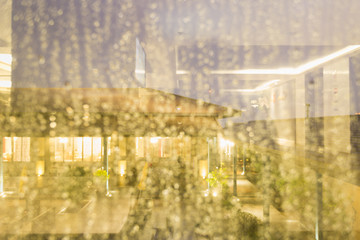 Urban night scene through rainy window, expressing melancholy and solitude.