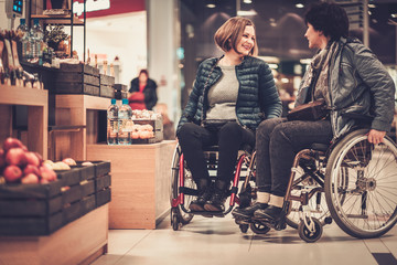 Two smiling disabled women in wheelchair in a department store