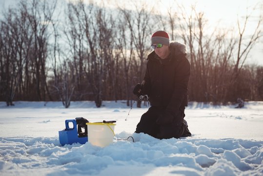 Ice fisherman fishing in snowy landscape