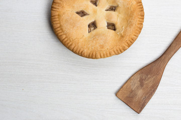 Apple pie cake lying on wooden white background with spoon