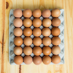 Top view of a paper egg tray filled with mostly brown eggs and a few white ones, showing natural diversity and balance in food presentation.