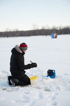 Ice fisherman fishing in snowy landscape