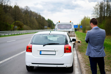 Man calling while tow truck picking up his broken car