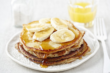 Stack of pancakes with banana and maple syrup
