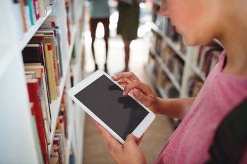 Schoolboy using digital tablet in library