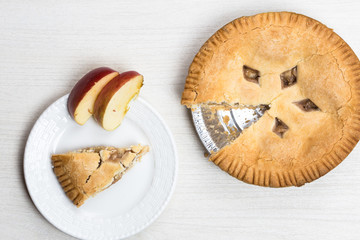 Apple pie cake lying on wooden white background on plate