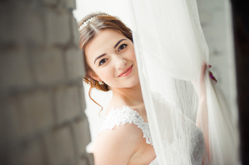 Beautiful bride with bouquet before wedding ceremony near window