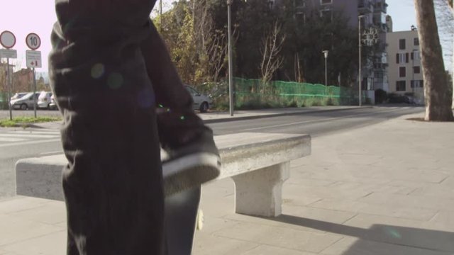 SLOW MOTION CLOSE UP: Unrecognizable skateboarder jumping and sliding on concrete bench on street. Closeup of skater's legs skateboarding and doing freestyle grinding trick with skateboard in a city