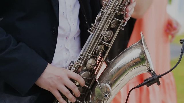 Saxophonist in black suit play jazz on golden saxophone with microphone. Music. Live performance