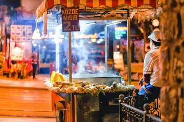 Stoff pro Meter Male street fast food seller with pan corn on traditional turkish cart. Istanbul, Turkey. Night scene. © Feel good studio