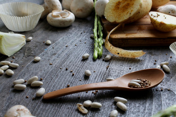 Fototapeta premium Grey wooden table with vegetables, onions, mushrooms, peppers, asparagus and spices. Process of cooking. Concept food. cooking.