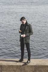 Fototapeta premium handsome young man in sunglasses listening to music near water