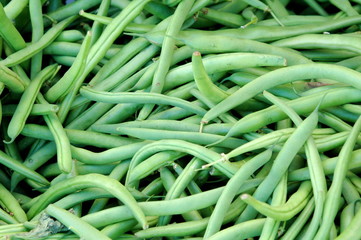 Green string beans displayed at produce stand outside.
