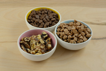 Chocolate chips, peanut butter chips and walnut toppings in bowls
