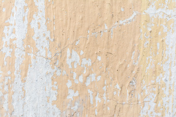 The texture of the plastered wall and carelessly partially painted in peach color, abstract background