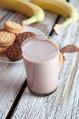 Photo of fresh Made Chocolate Banana Smoothie on a wooden table with cookies.