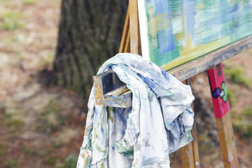Young brunette woman artist, painting in canvas. Outdoors, in nature.