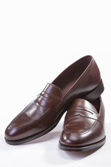 Footwear Concepts. Leather Stylish Brown Penny Loafer Shoes Together Against White Background.