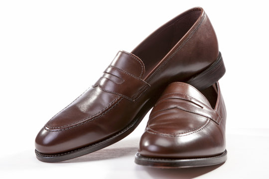 Footwear Concepts. Leather Stylish Brown Penny Loafer Shoes Together Against White Background.